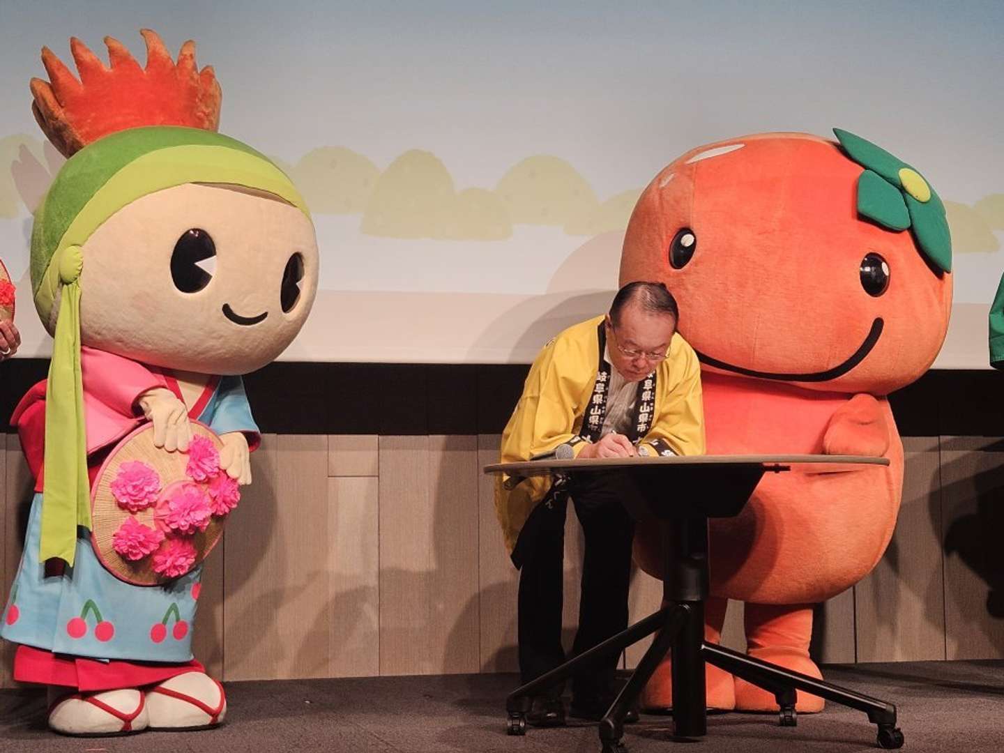 サインする林市長と、見守るナッチョルくん・はながたベニちゃん（画像は編集部撮影）