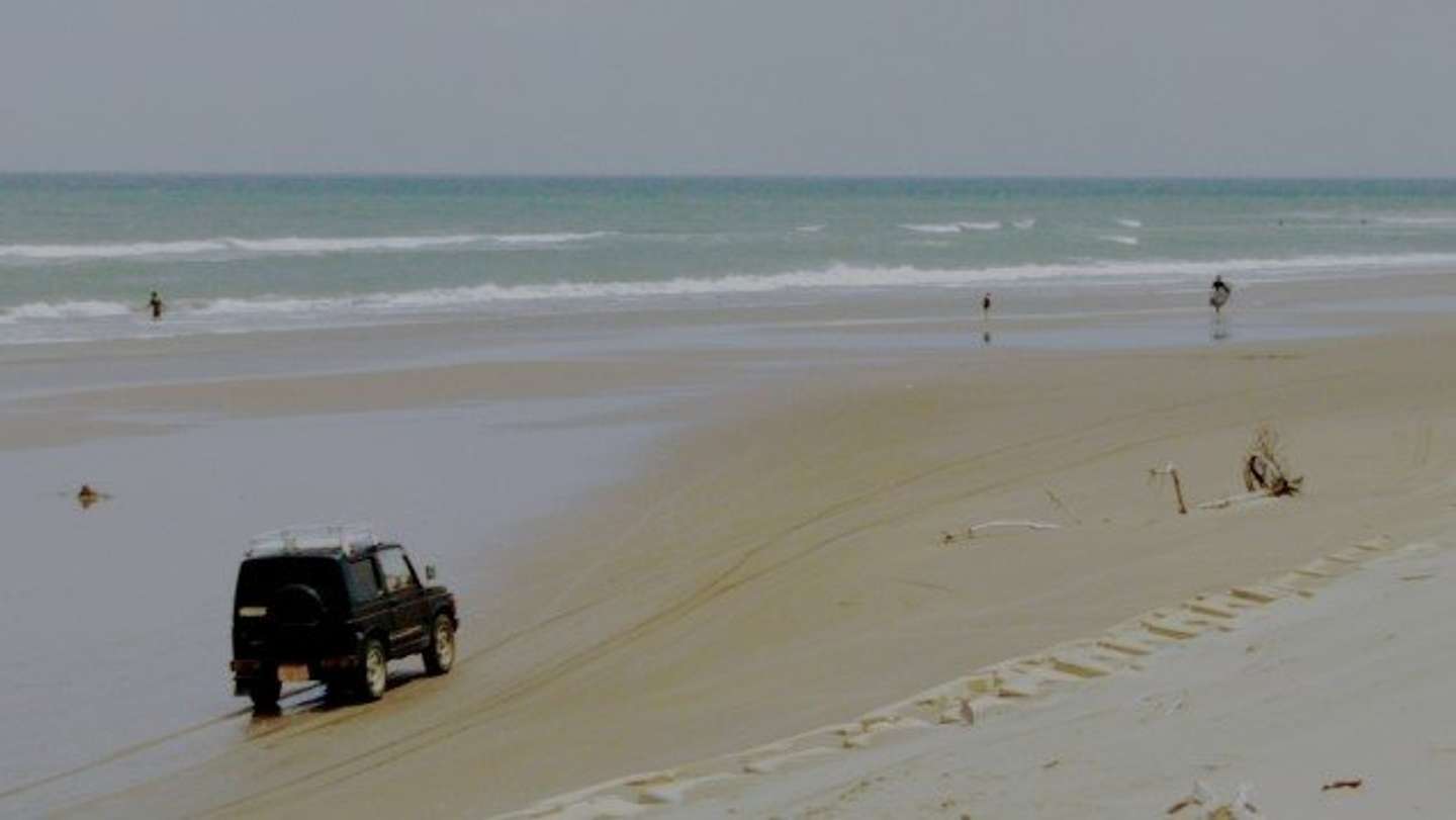 砂浜にハマった車を若者たちが（画像はphotoAC）